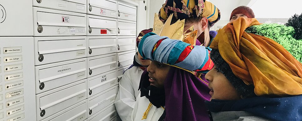Sternsinger stehen Postkasten und klingeln an Haustüre