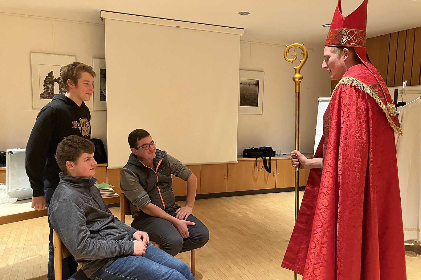 Ein Teilnehmer übt seinen Auftritt als Nikolaus-Darsteller vor anderen Teilnehmer:innen der Nikolausschule