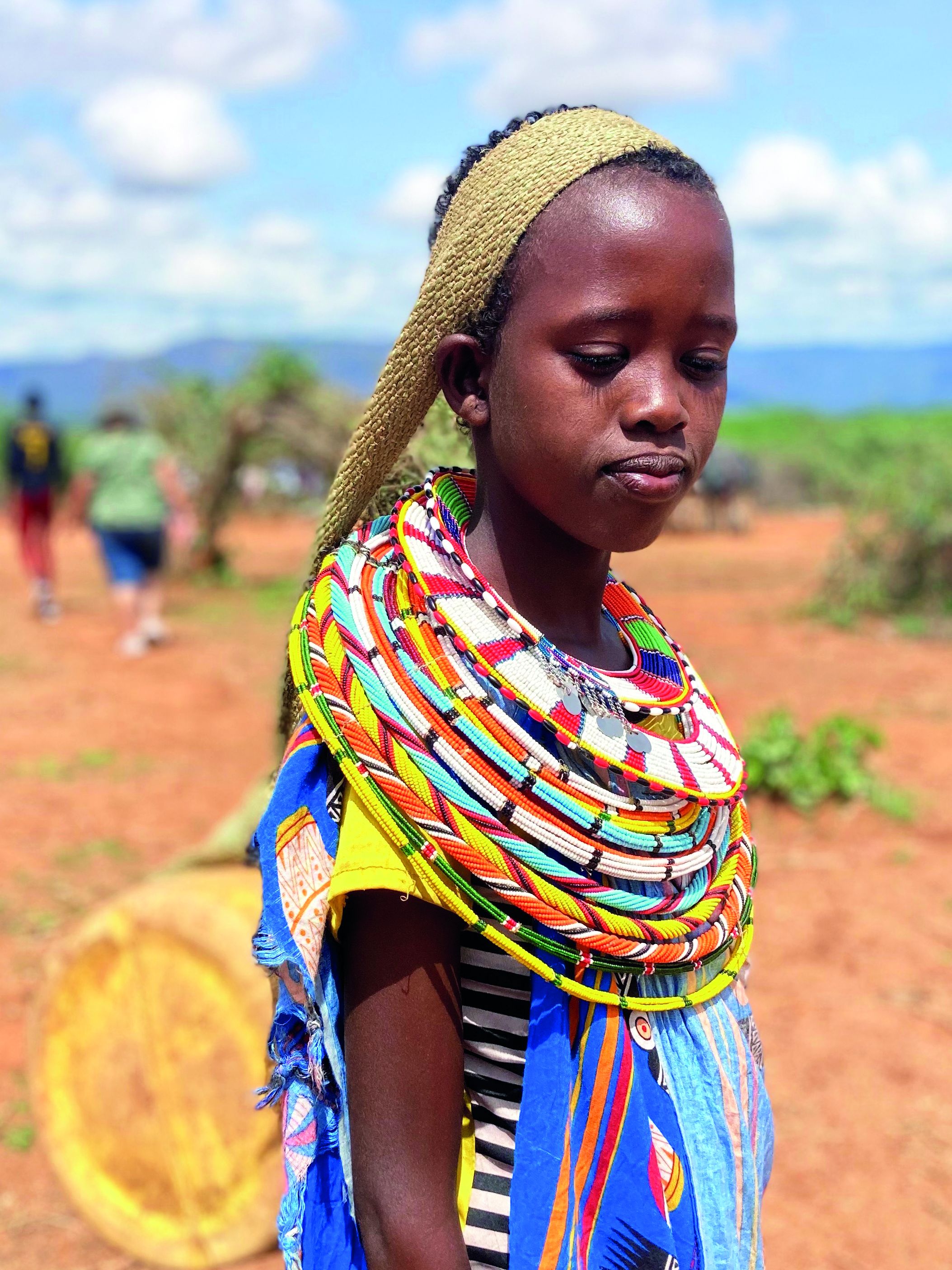 Mädchen auch Kenia mit traditionellem Perlenschmuck trägt Kanister mit Wasser