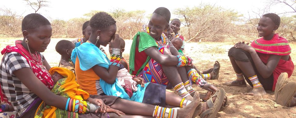 Frauen aus Kenia sitzen gemeinsam mit ihren Kindern zusammen und diskutieren miteinander