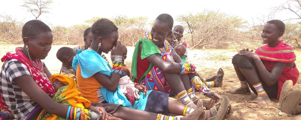 Frauen und Kinder aus Kenia sitzen beisammen und diskutieren miteinander