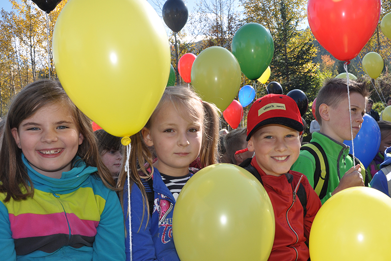 Kinder lachen und haben mit Helium gefüllte Luftballons in den Händen